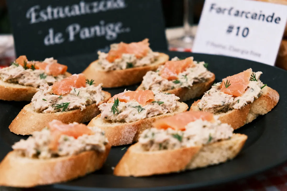 Assiette de bruschettas garnies de mélange de poisson, saumon fumé et brins d'aneth, sur fond noir.