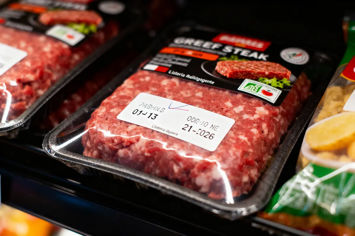 Paquets de haché de viande de bœuf emballés avec étiquettes, exposés dans un réfrigérateur en magasin.