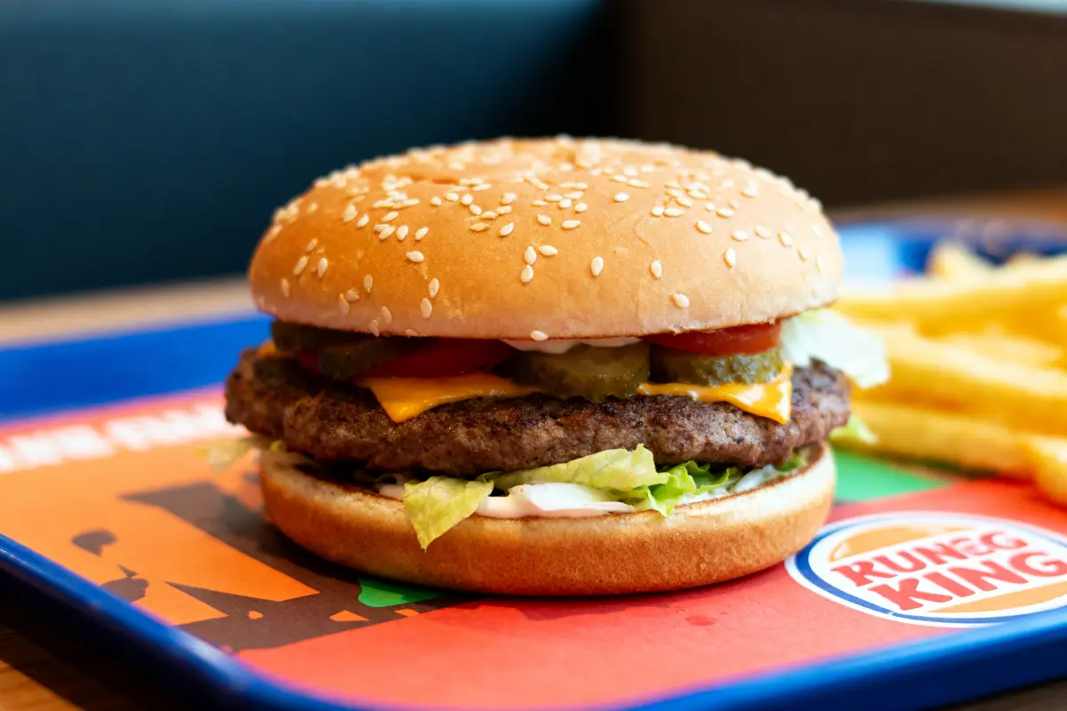 Burger King halal hamburger avec fromage, cornichons et frites sur un plateau coloré