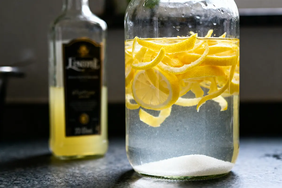 Tranches de citron dans bocal avec alcool pour recette de limoncello maison.